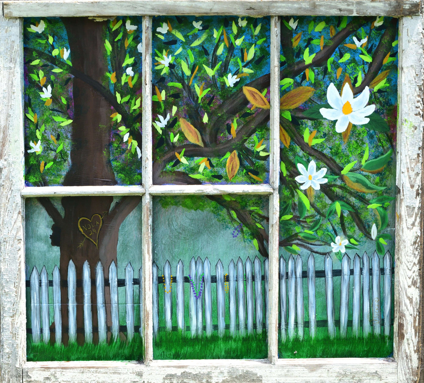 Old window frame with a painting of an old Magnolia tree with white picket fence with beads hanging, heart carved in tree trunk